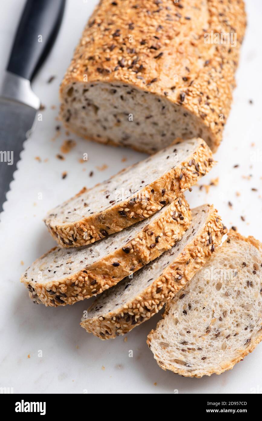 Multigrain bread with seeds sliced on marble texture. Healthy whole grain bread Stock Photo