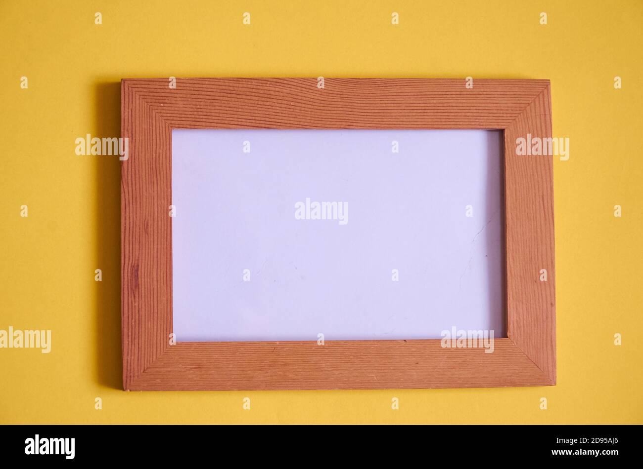 An empty wooden photo frame lies on a yellow background. Mock up Stock Photo