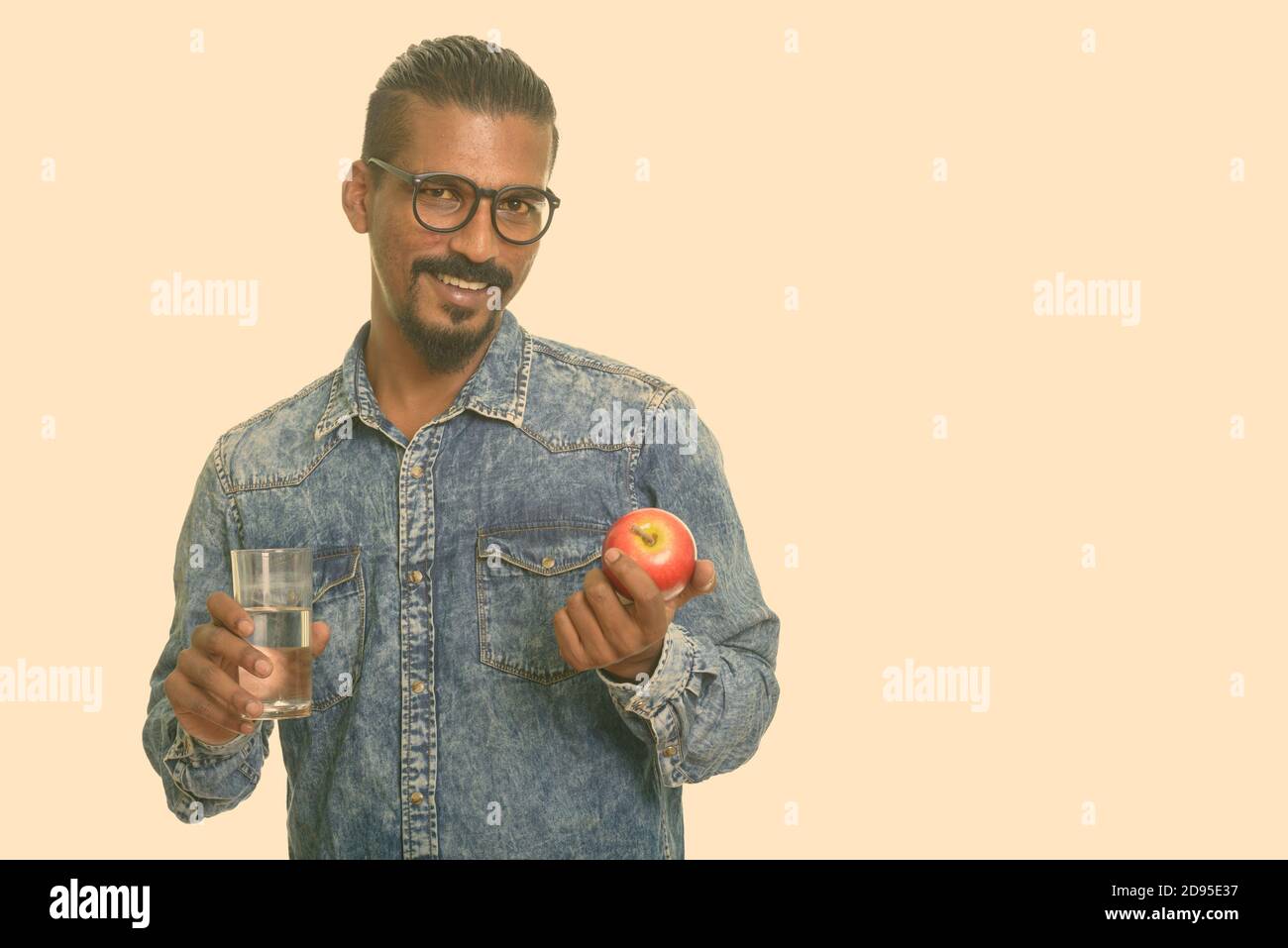 Young happy Indian man holding red apple and glass of water Stock Photo ...