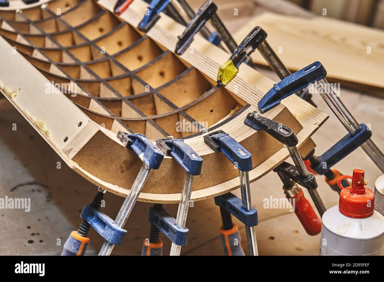Joinery. Plywood bending process close-up. Gluing and clamping bend wooden panel. Bend furniture manufacture Stock Photo