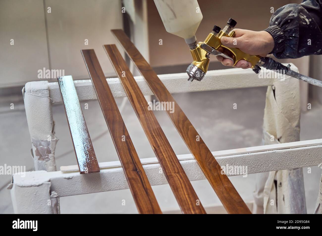 Man painting furniture details in a spray booth. Worker using spray gun
