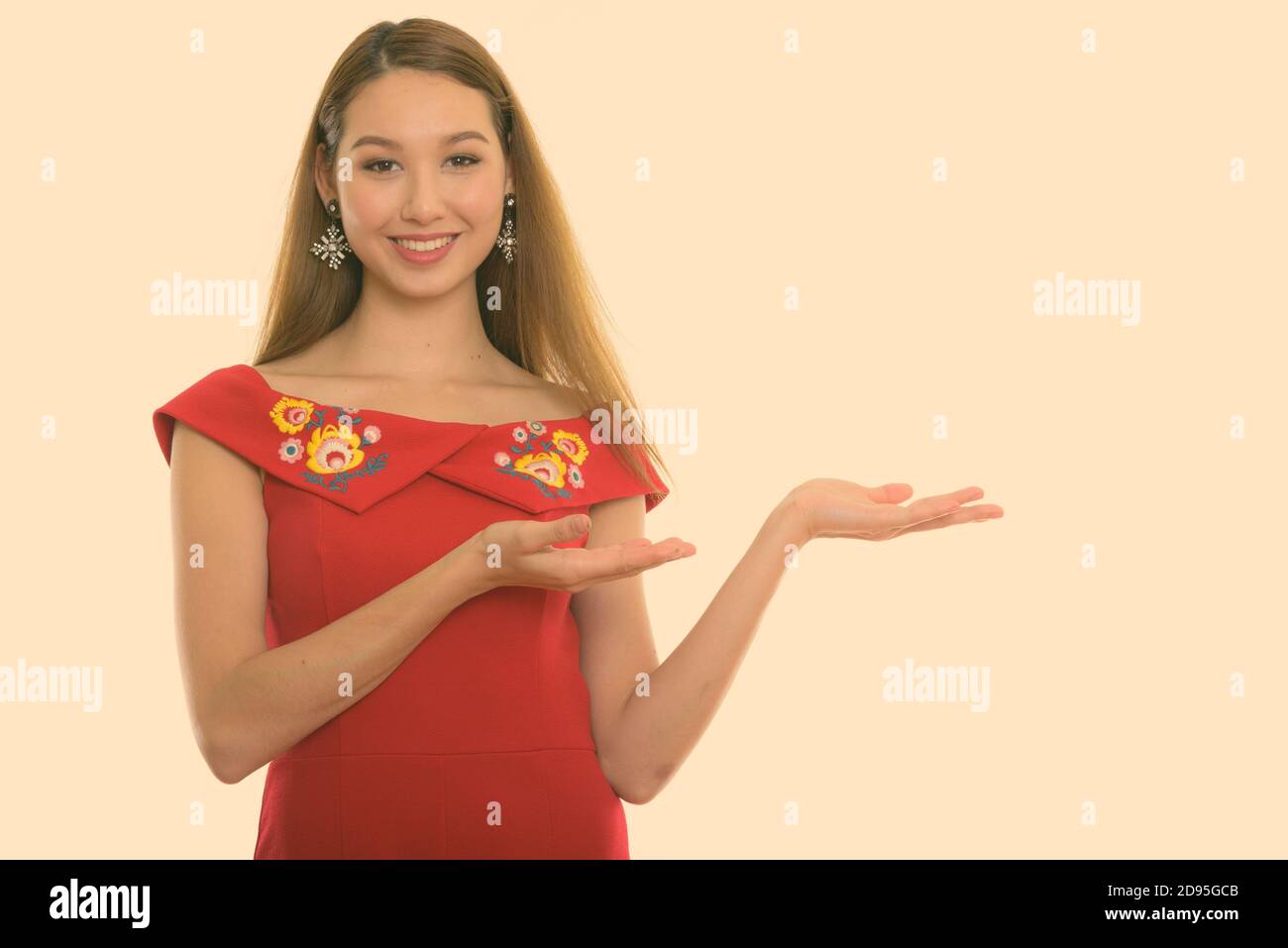 Studio shot of young happy beautiful Asian woman smiling while showing ...
