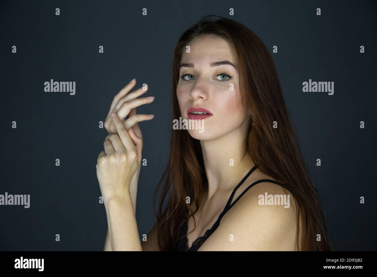 Shot of young brunette woman with long hair on dark background Stock Photo