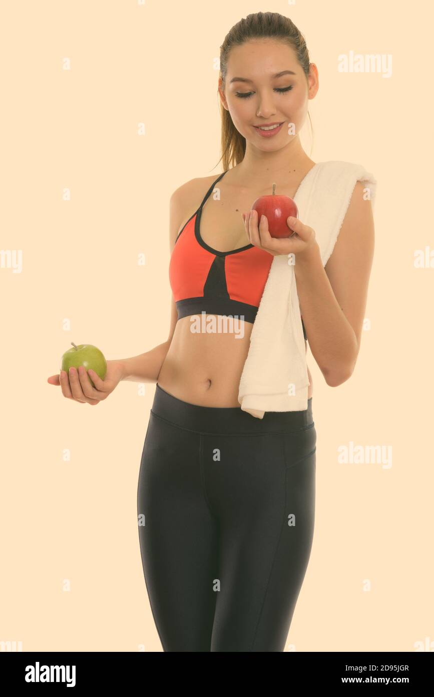 Studio shot of young happy beautiful Asian woman smiling and standing ...