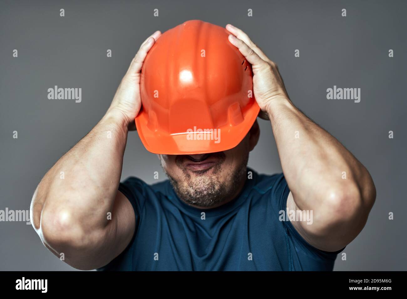 Extremely stressed engineer in hardhat against gray background Stock Photo