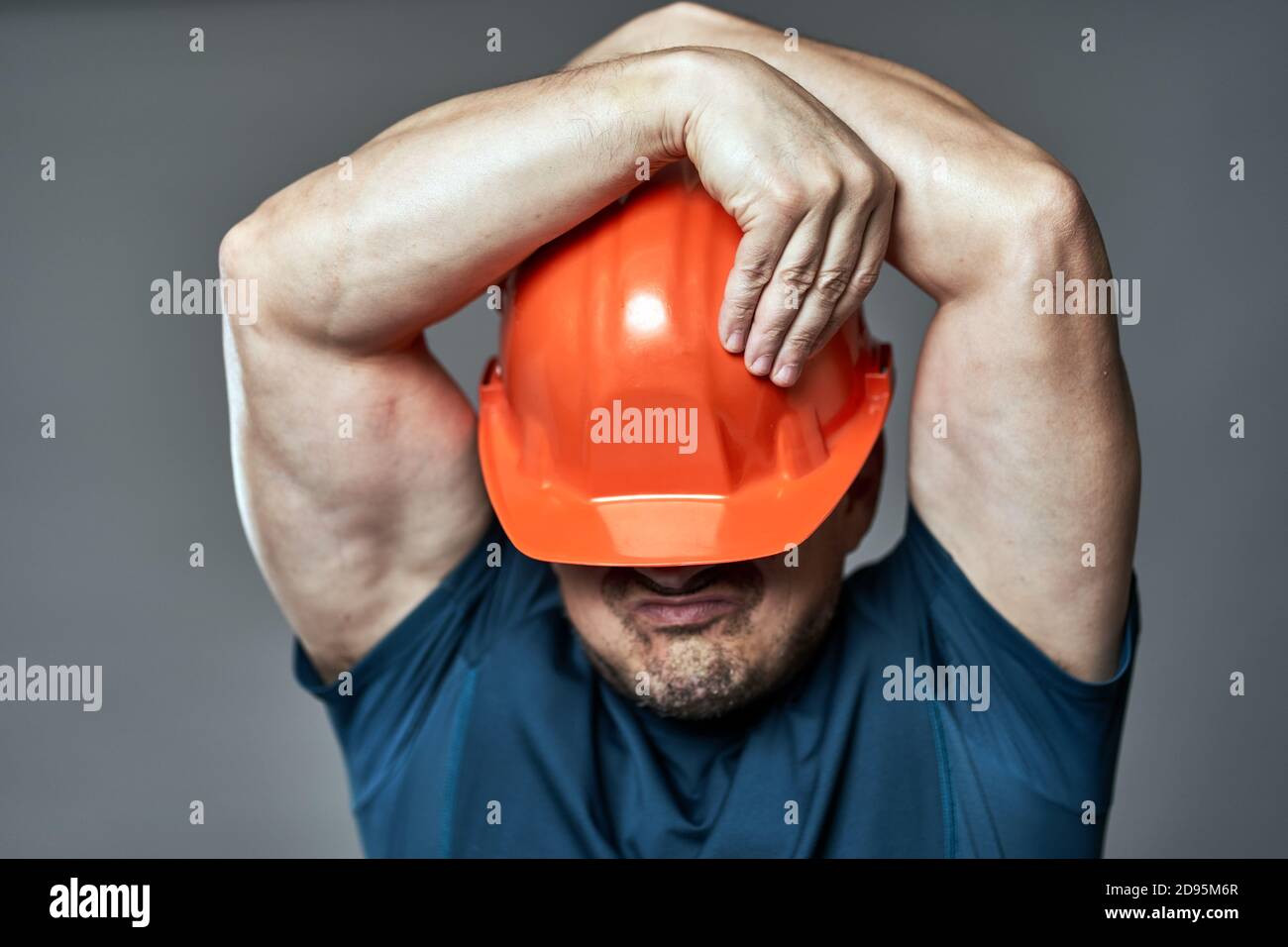 Extremely stressed engineer in hardhat against gray background Stock Photo