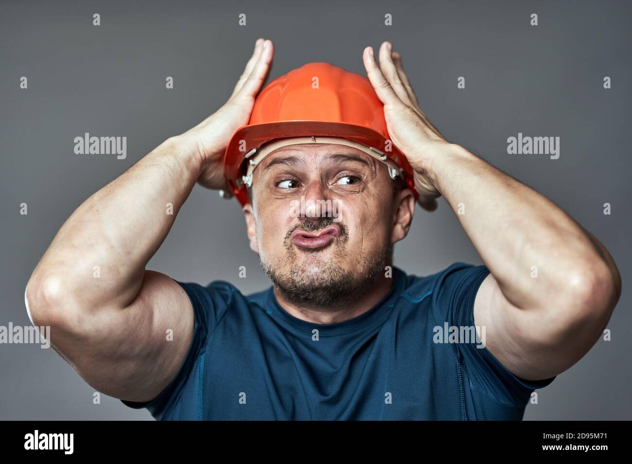 Extremely stressed engineer in hardhat against gray background Stock Photo