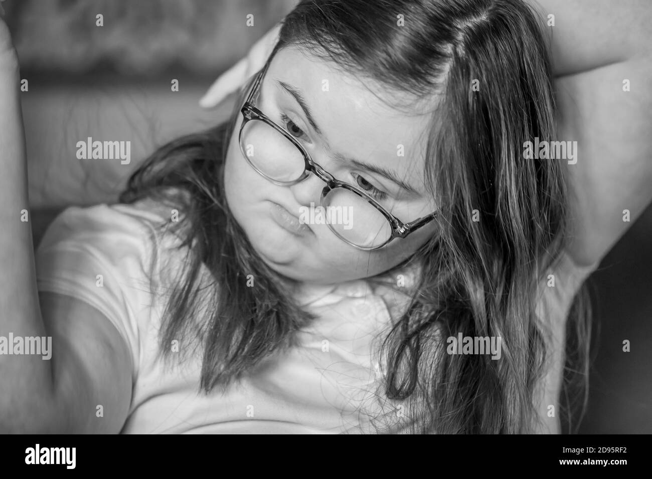 Young female teenage with Downs Syndrome brushing her hair indoors, Northampton, England, UK. Stock Photo