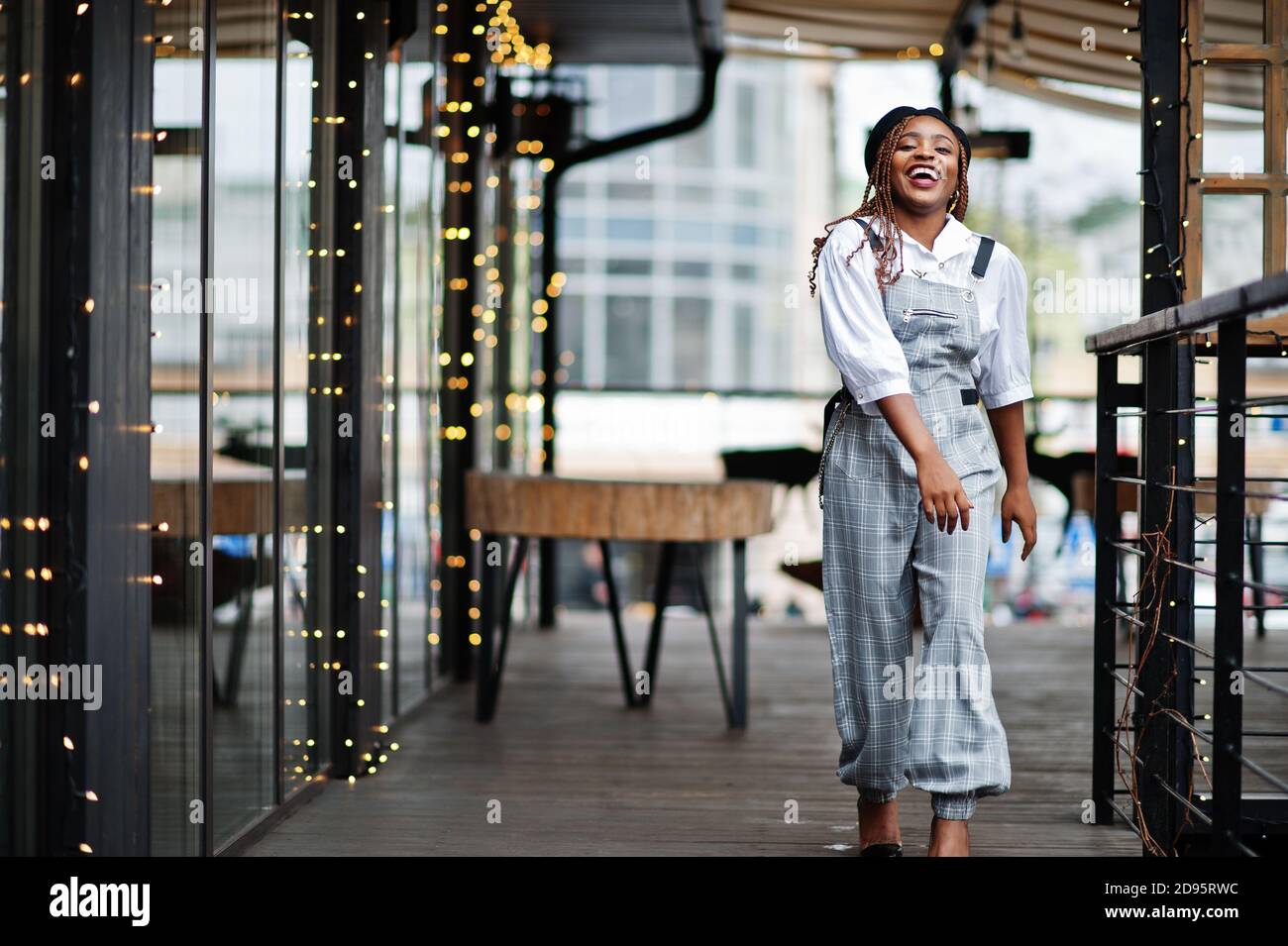 African American Woman In Overalls And Beret Posed In Outdoor Terrace With Christmas Decorations 4142