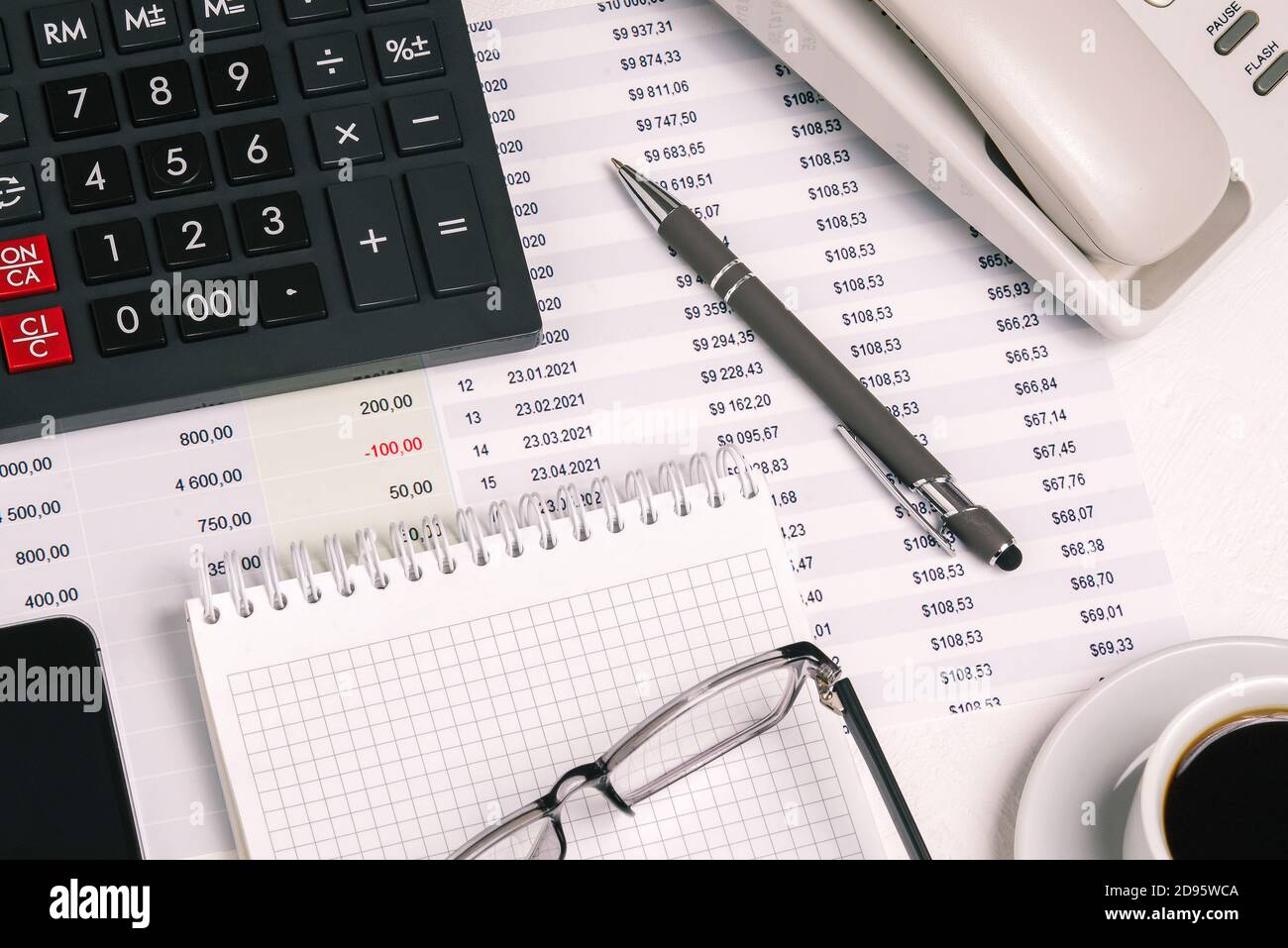 Financial analysts desktop with a calculator, coffee Cup, pen, Notepad, and documents Stock Photo