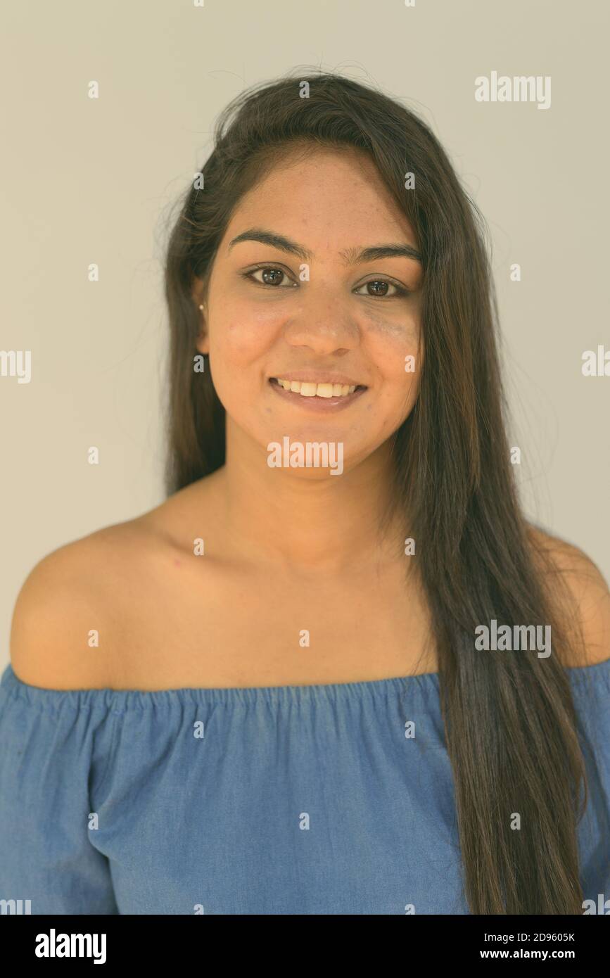 Face of young happy Indian woman smiling against blue background Stock Photo
