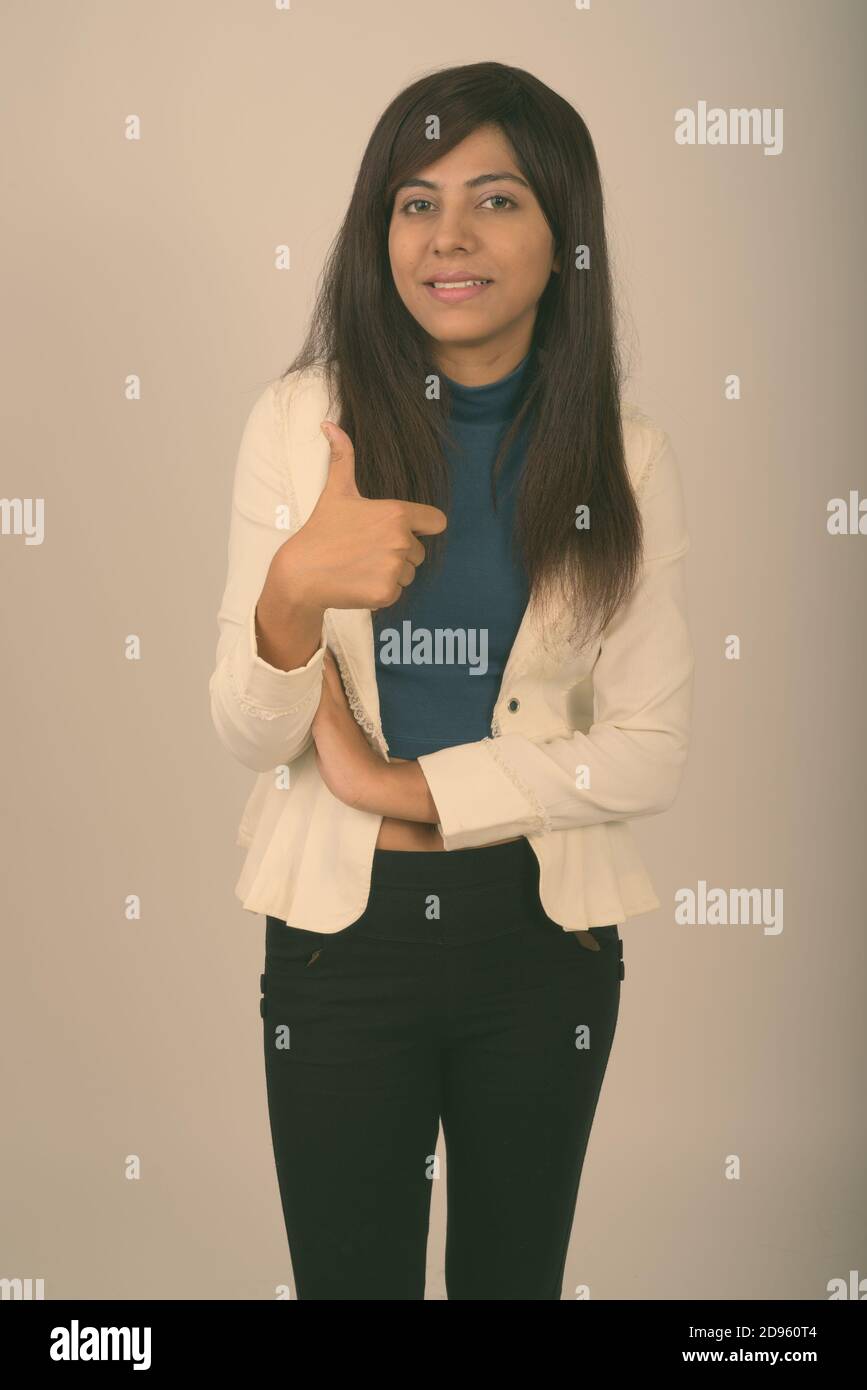 Studio shot of young happy Persian businesswoman smiling while giving ...