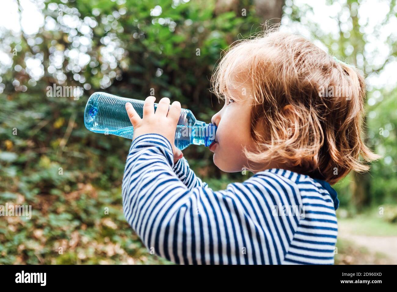 https://c8.alamy.com/comp/2D960XD/little-blond-haired-girl-drinking-water-from-a-plastic-bottle-during-an-excursion-in-nature-2D960XD.jpg