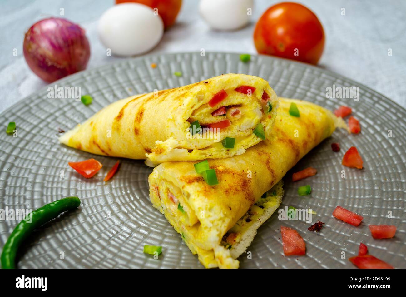 Half cut Egg Omelette Dosa in a plate with tomato, eggs & onions Stock Photo