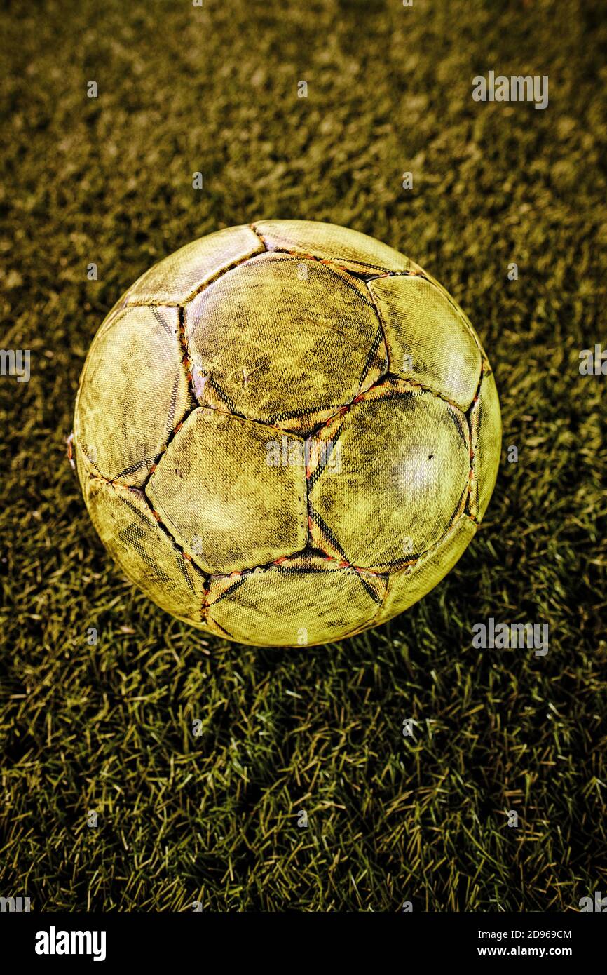 A worn well used football/ soccer ball on an artificial grass astro turf indoor soocer / football pitch. Stock Photo