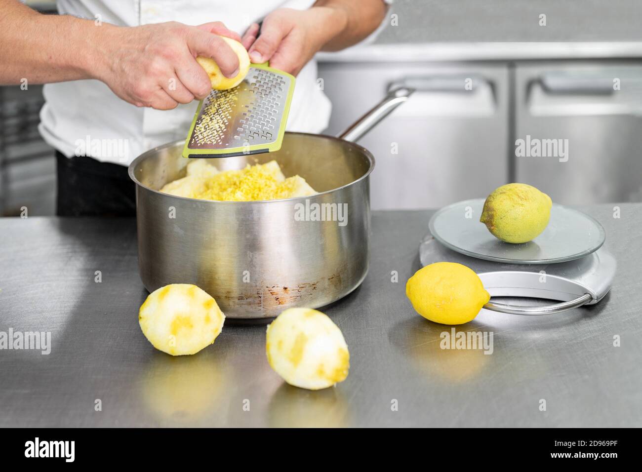 A Pastry chef's hand grates lemon in commercial kitchen. Chef grates limes on the grater to get
