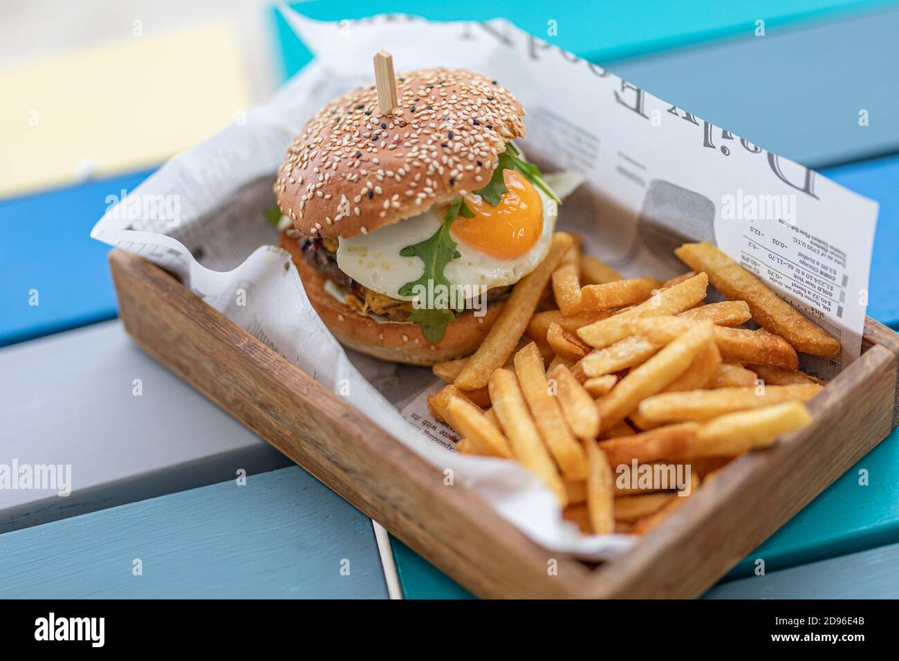 Close-up of beef burger on wooden table background. Hamburger grilled meat burger, lettuce, tomato and fried egg. Gourmet handmade burger Stock Photo