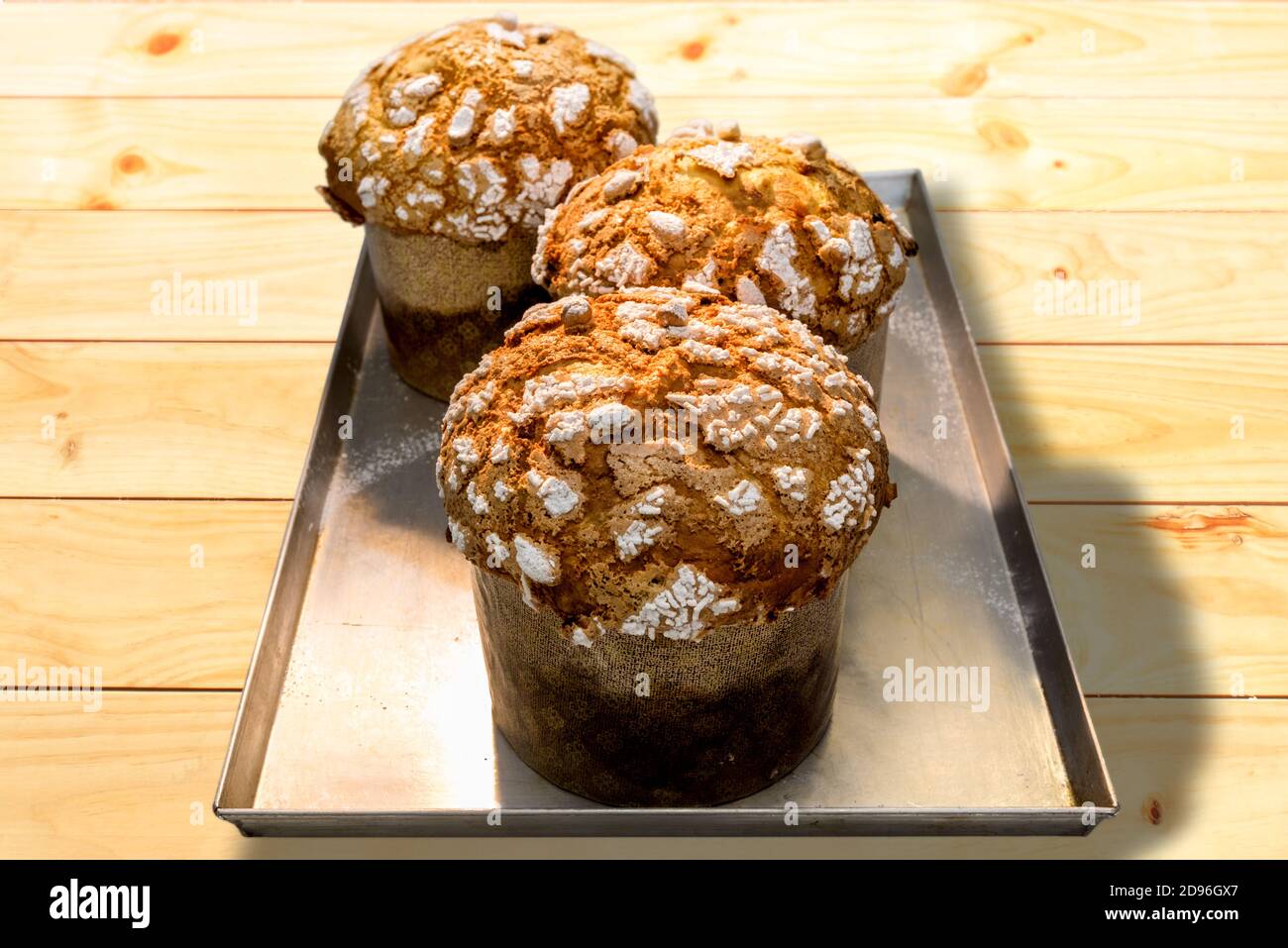 Panettone, typical Italian Christmas cake from Milan, freshly baked on baking sheet and wooden background Stock Photo