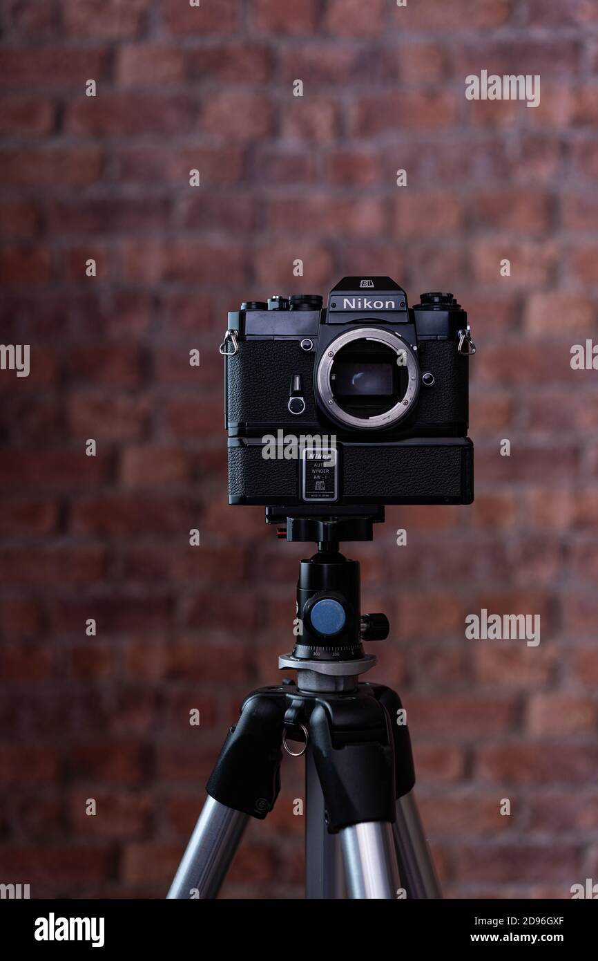 A vintage Nikon EL2 SLR camera on a tripod with a brick background Stock Photo