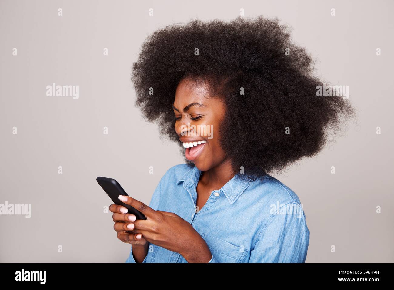 Close up side portrait of happy young black woman laughing at text ...