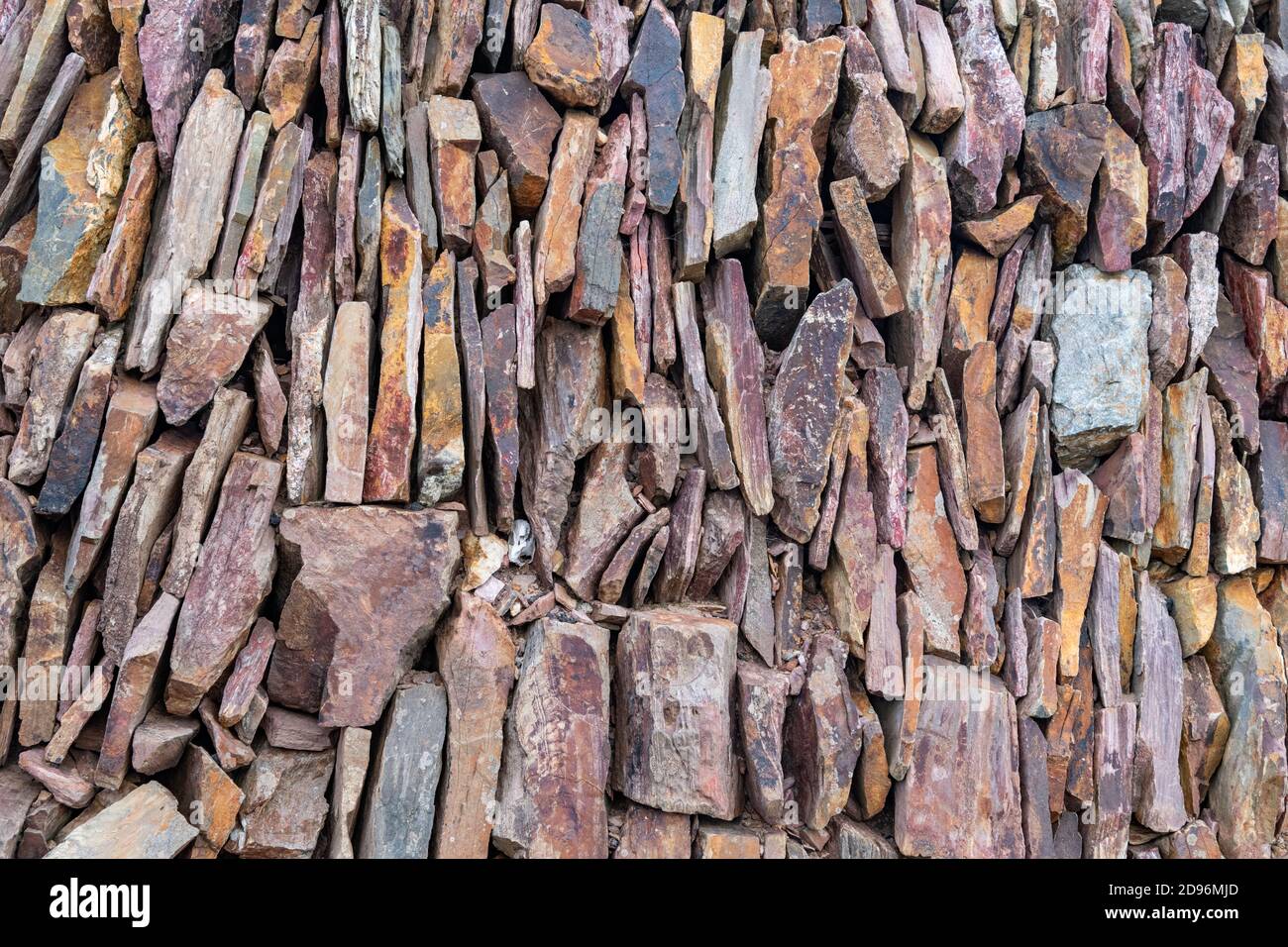 close up shot of a slate stone wall with varying colours of purple and grey Stock Photo