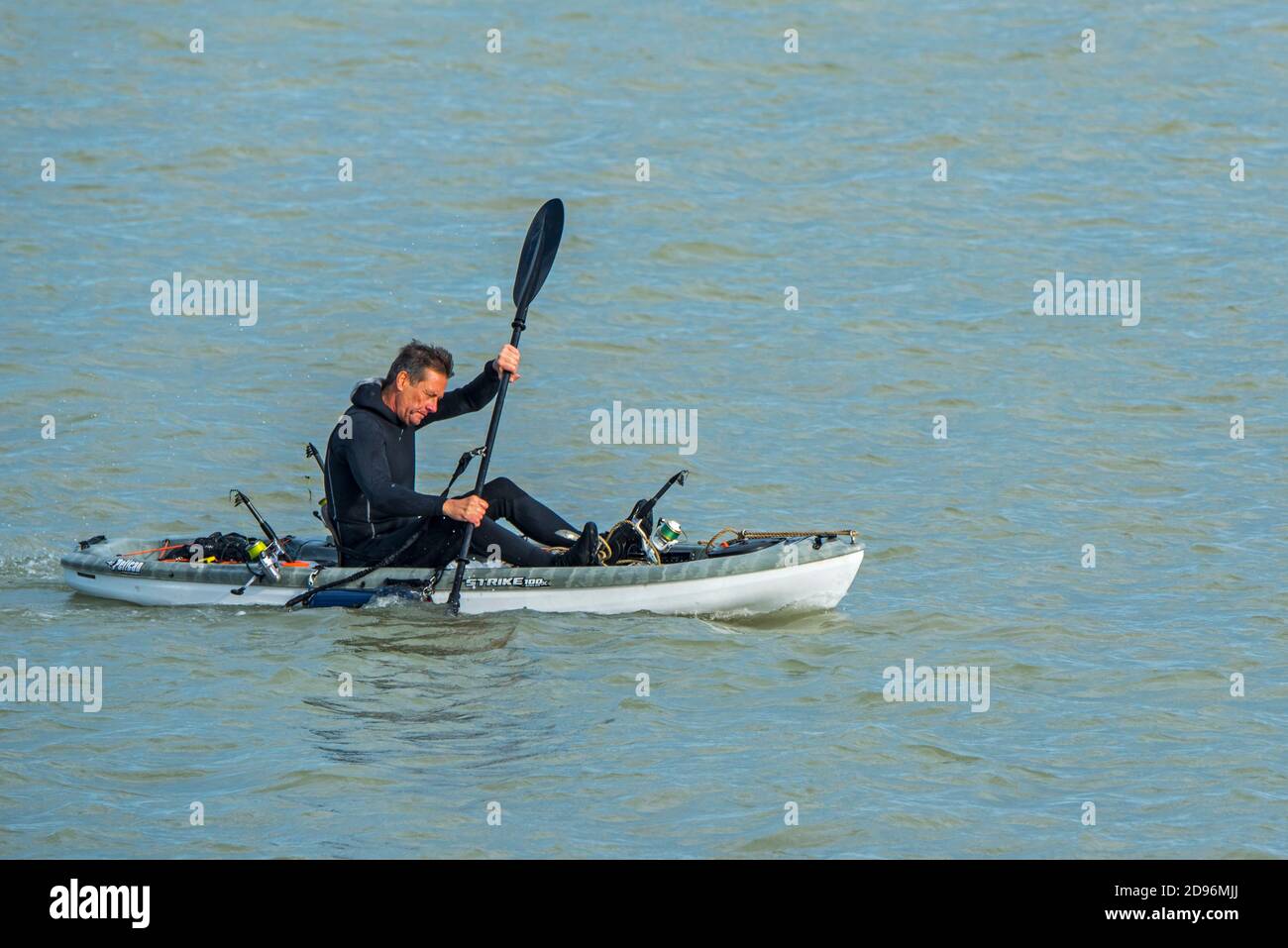 Sea angler in wetsuit paddling on the North Sea in Pelican Strike 100X Angler Kayak Stock Photo