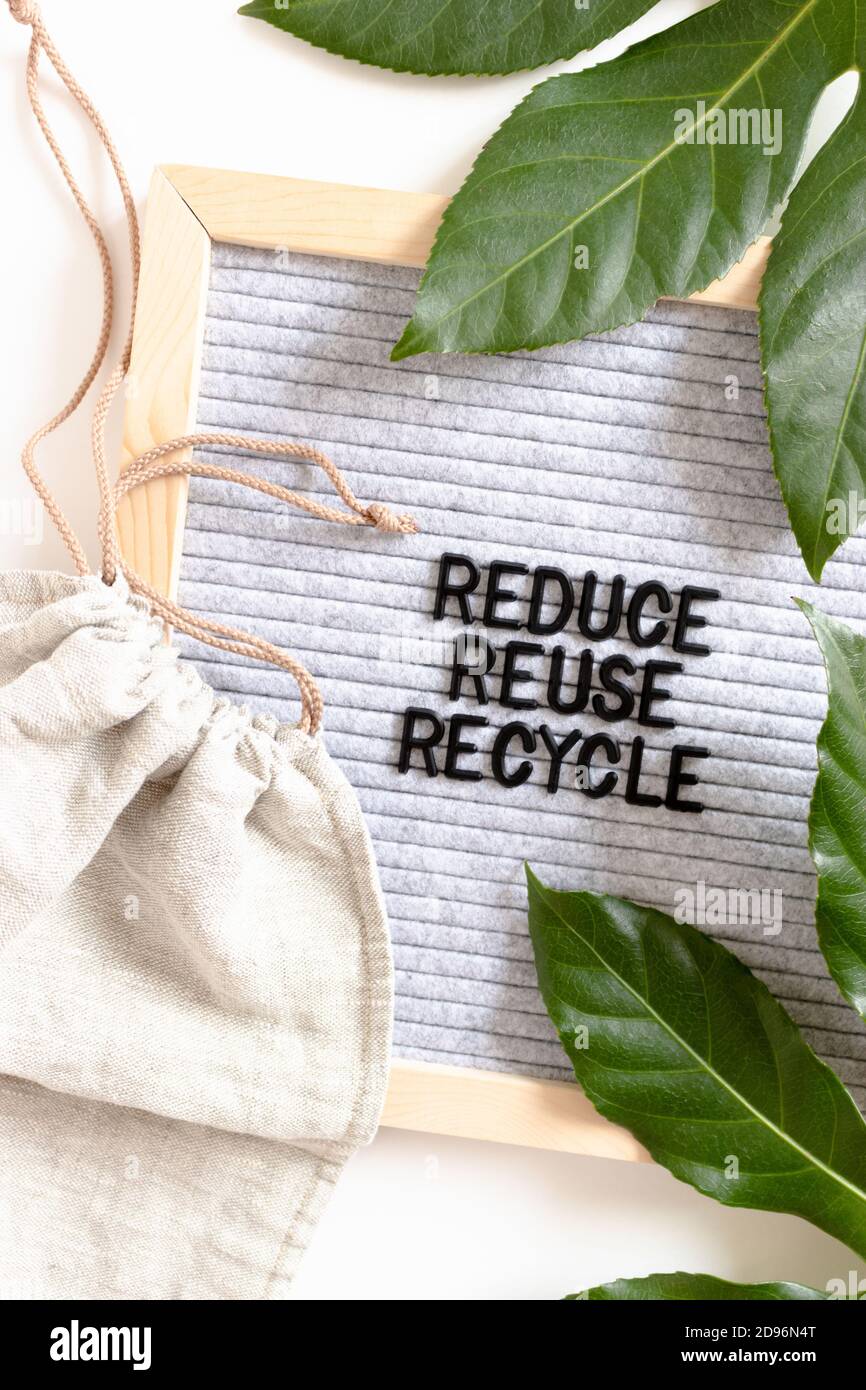 Green leaves, canvas bag and letterboard with quote Reduce Reuse ...