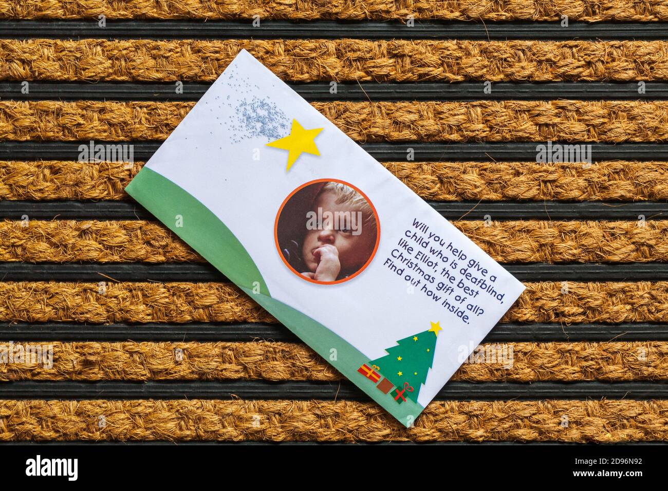 Post mail on doormat - charity appeal from Sense,  Will you help give a child who is deafblind, like Elliot, the best Christmas gift of all? Stock Photo
