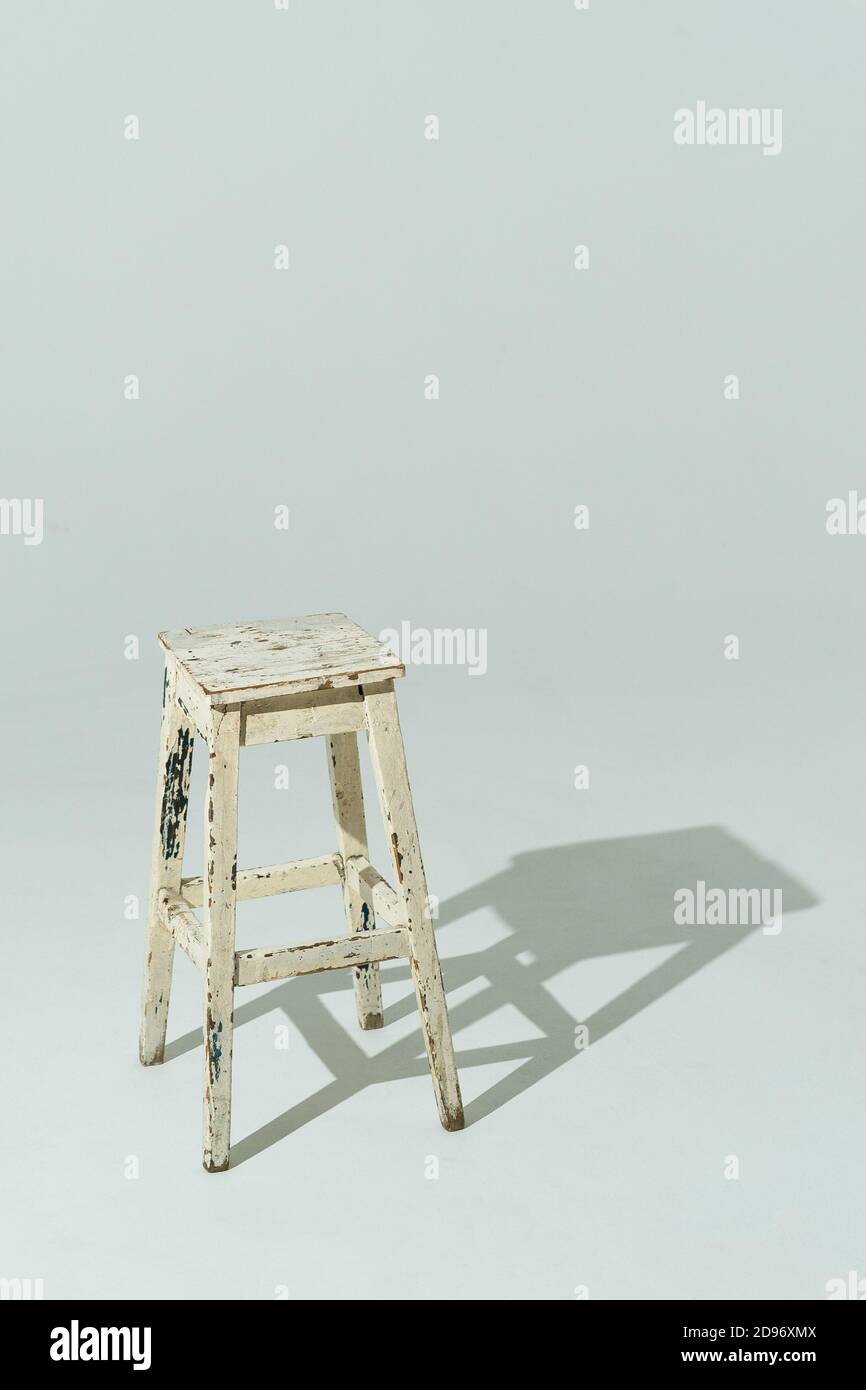 Authentic wooden chair with old dairy color paint. White furniture on light studio background. Vertical format. Stock Photo