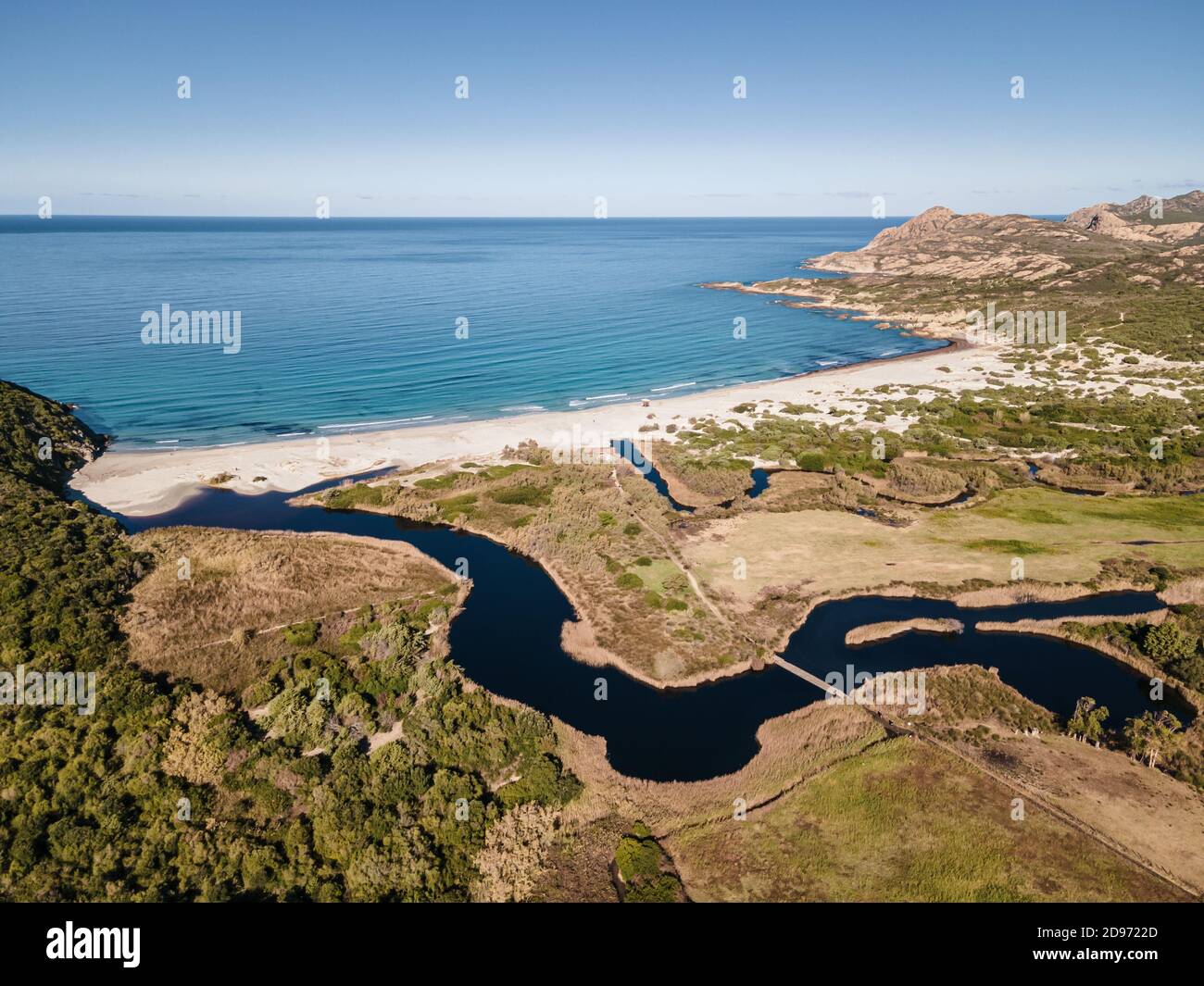 Aerial view of the turquoise mediterranean sea washing onto the white sandy beach of Ostriconi in the Balagne region of Corsica with a river winding i Stock Photo