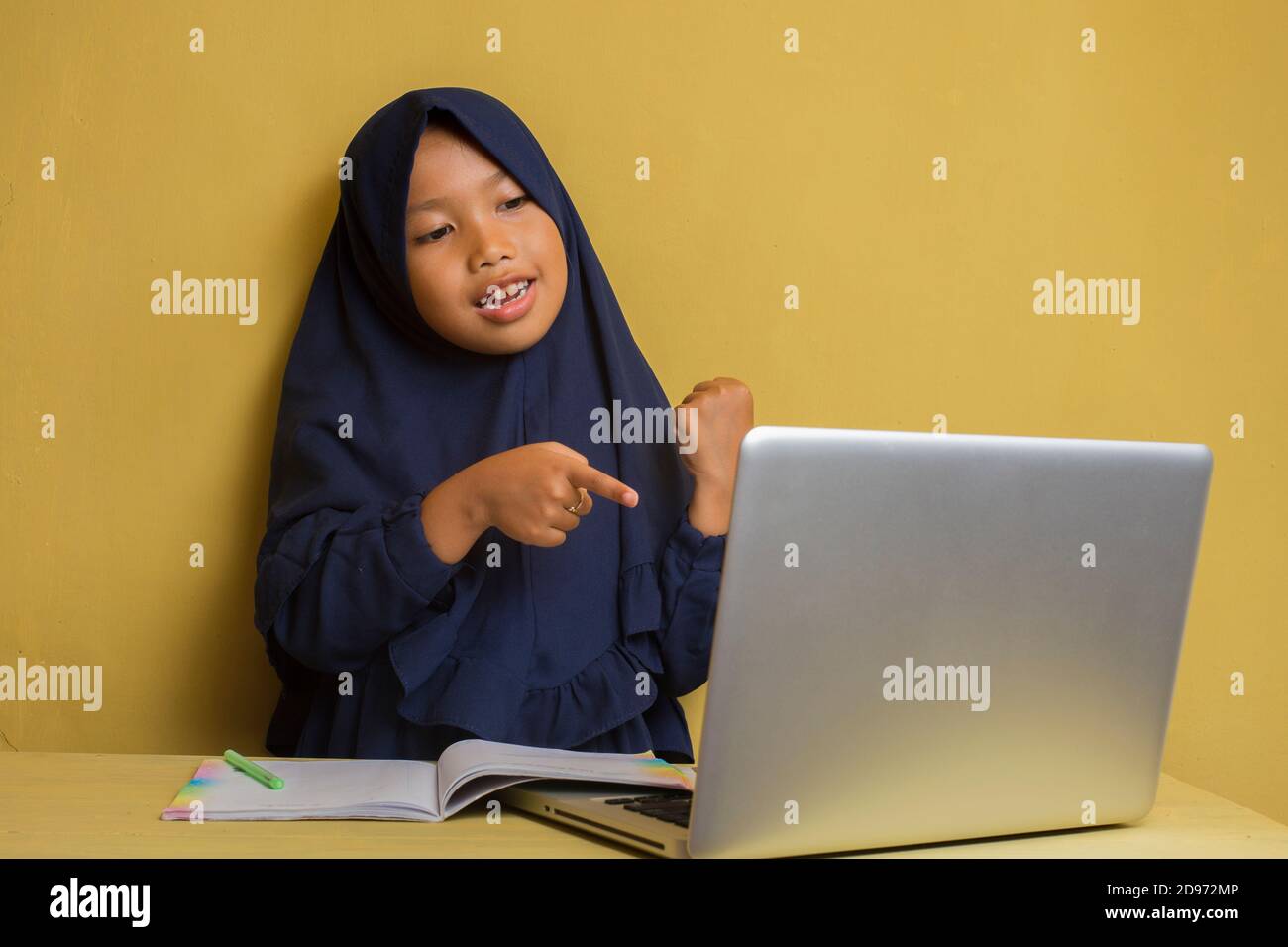Little asian muslim hijab girl using her laptop computer online video ...