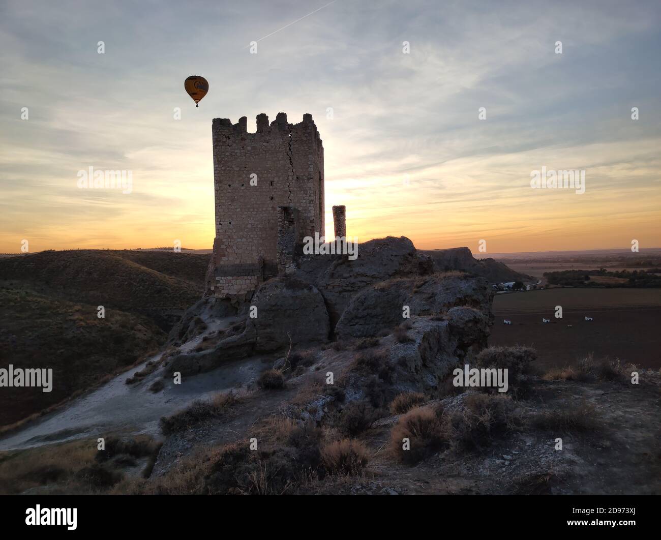 ONTíGOLA, SPAIN - Oct 17, 2020: Globo aerostatico Ultra Magic cruzando el atardecer sobre el Castillo de Oreja en Ontigola. Evento de globos organizad Stock Photo