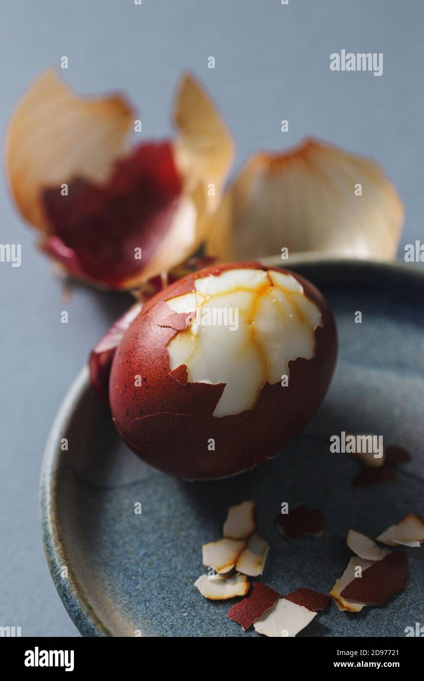 Close up of halfpeeled egg colored with natural dye onion skins