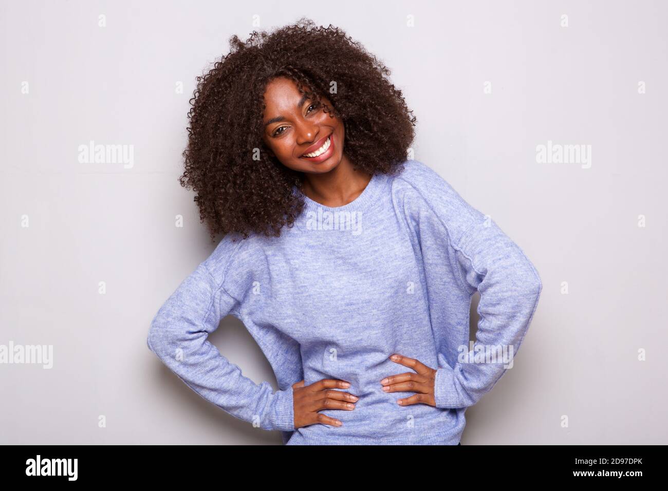Portrait of happy young african american woman standing with hands on ...