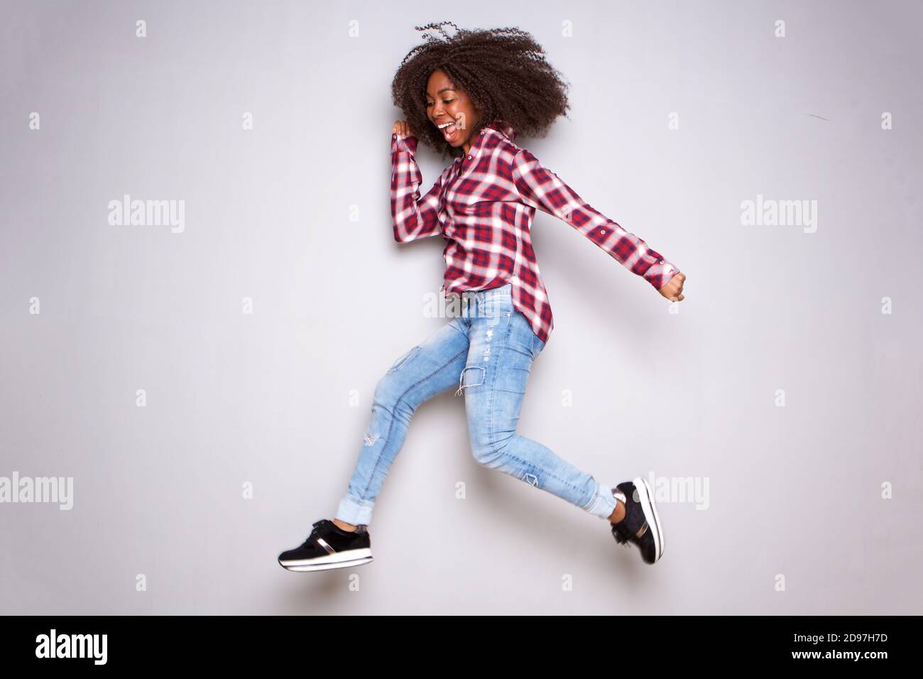Full length portrait of happy young african woman jumping over white ...