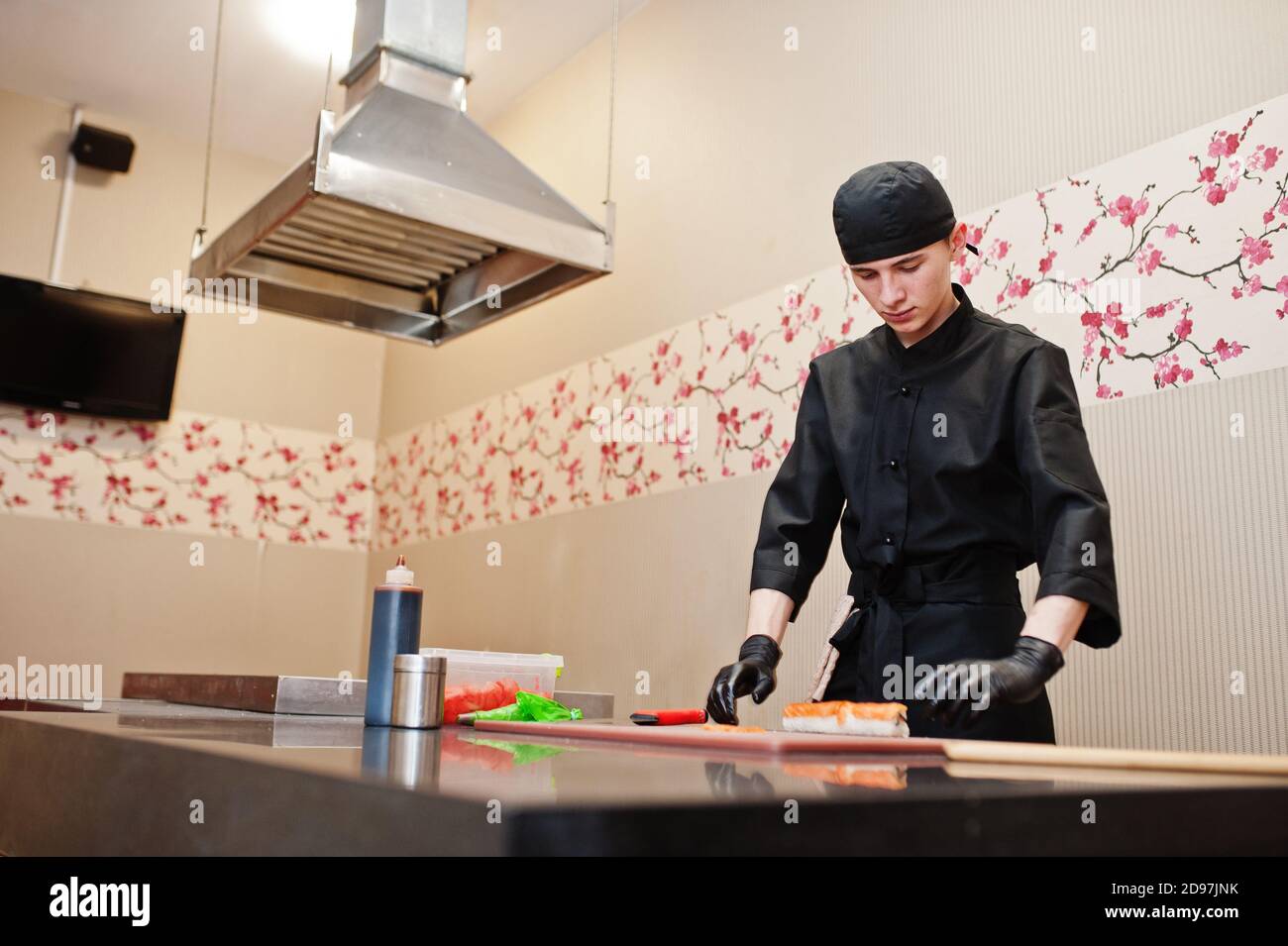 Professional Chef Wear In Black Making Sushi And Rolls In A Restaurant professional-chef-wear-in-black-making-sushi-and-rolls-in-a-restaurant