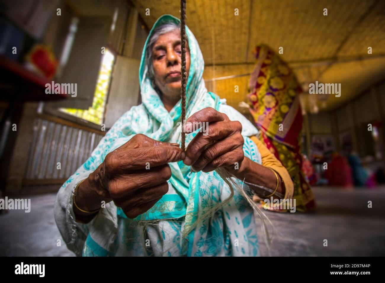 An old age woman is making on some fiber rope using on the banana tree