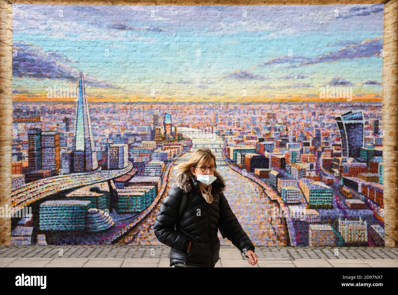 A woman wearing a protective face mask passes a mural by artist Jimmy C located on the South Bank, in London, Britain, November 3, 2020. REUTERS/Henry Nicholls Stock Photo