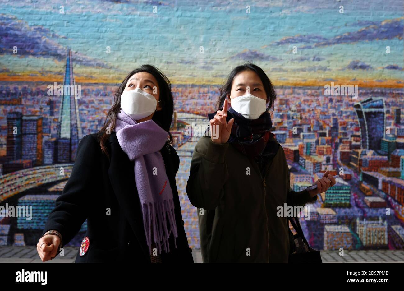 People wearing protective face masks pass a mural by artist Jimmy C located on the South Bank, in London, Britain, November 3, 2020. REUTERS/Henry Nicholls Stock Photo
