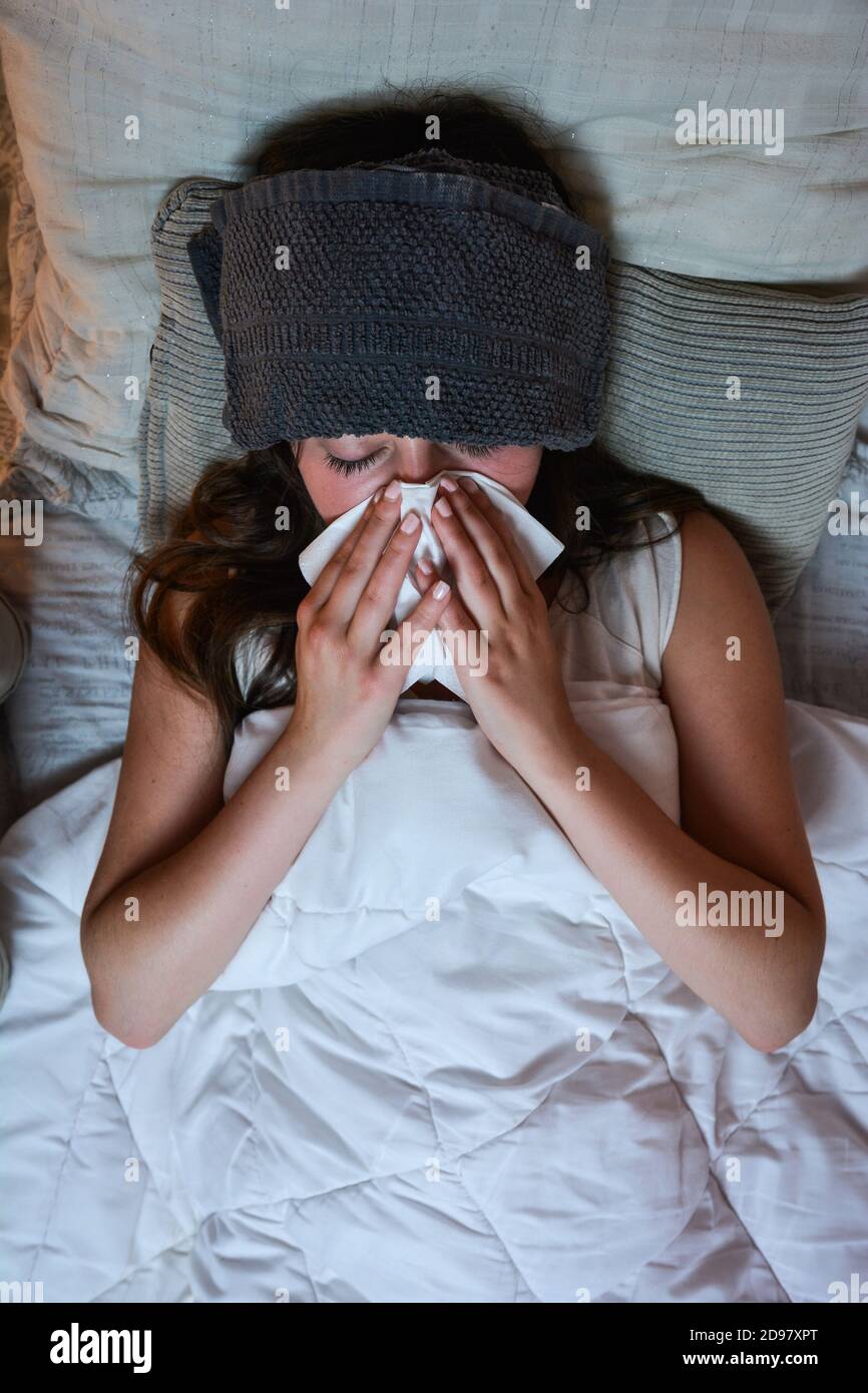 Teenage girl is very cold and feverish. She is lying on her bed. Stock Photo