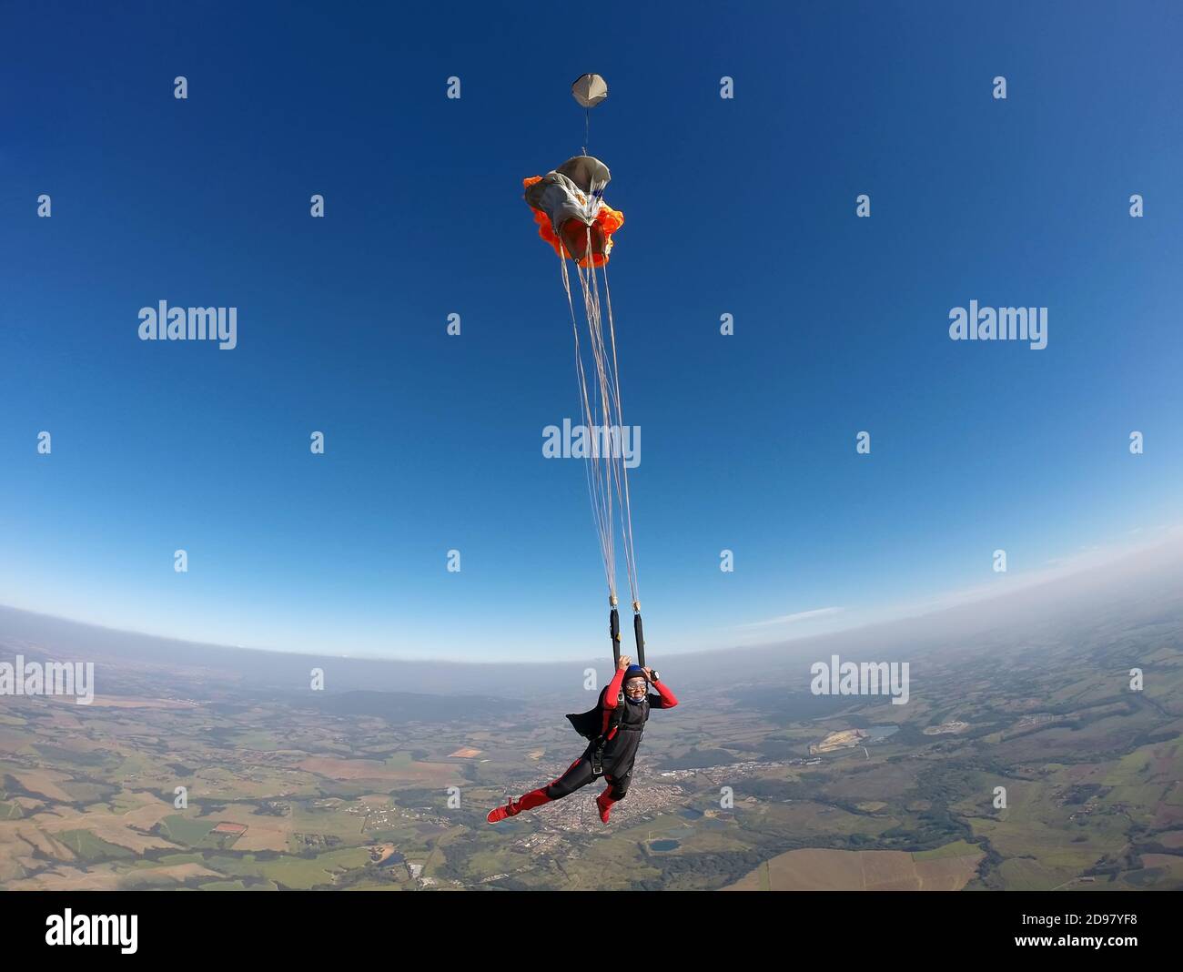 Smiling black woman jumping from parachute Stock Photo