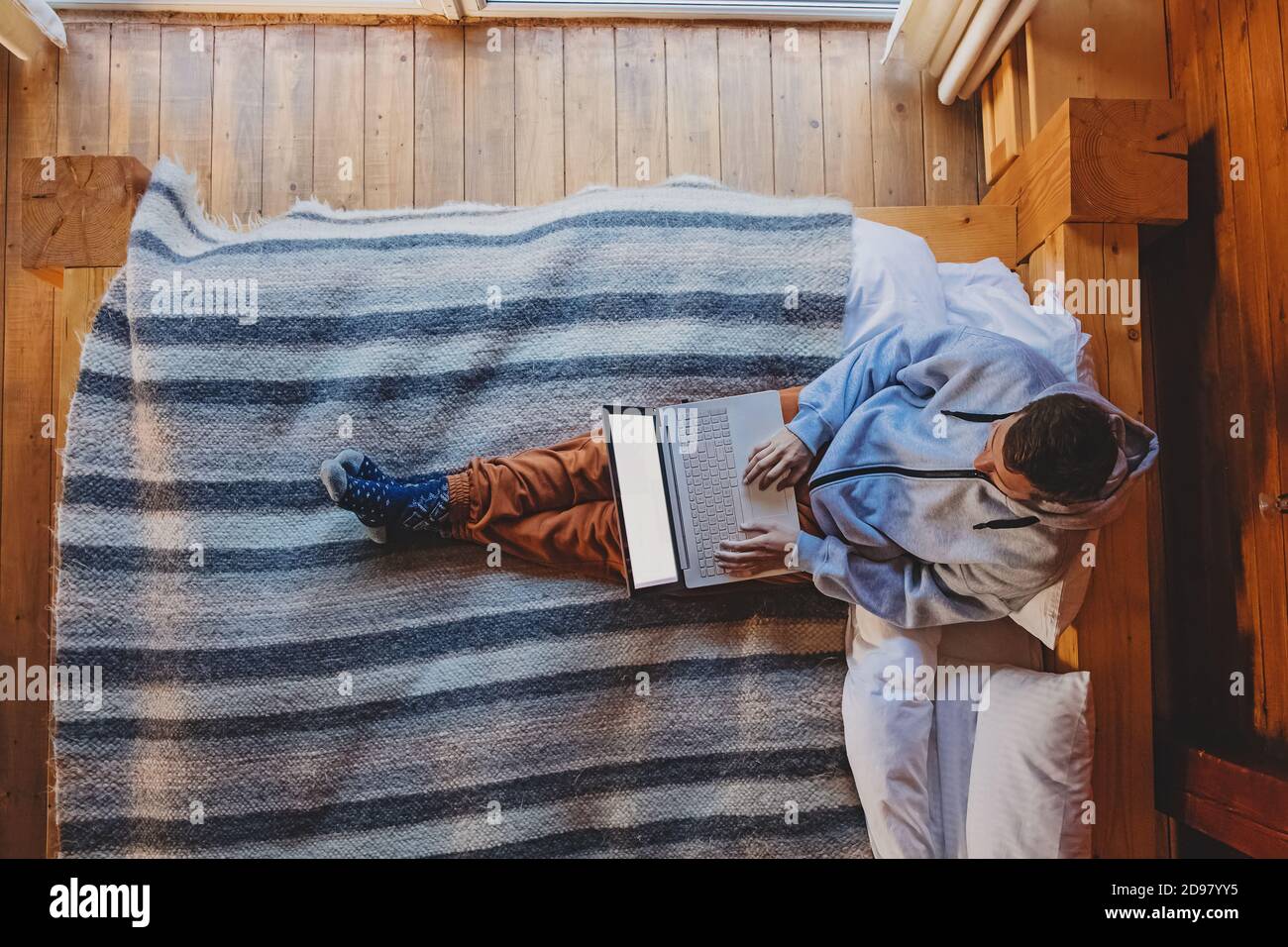 Man working on laptop sitting on cozy bed Stock Photo