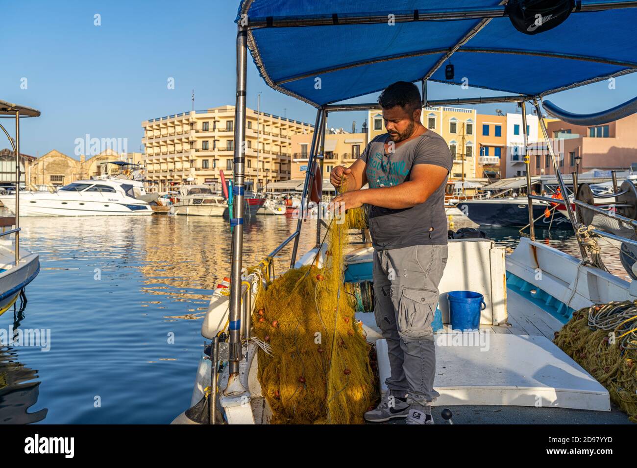 Fischer mit seinem Netz auf enem Boot im Hafen von Chania, Kreta