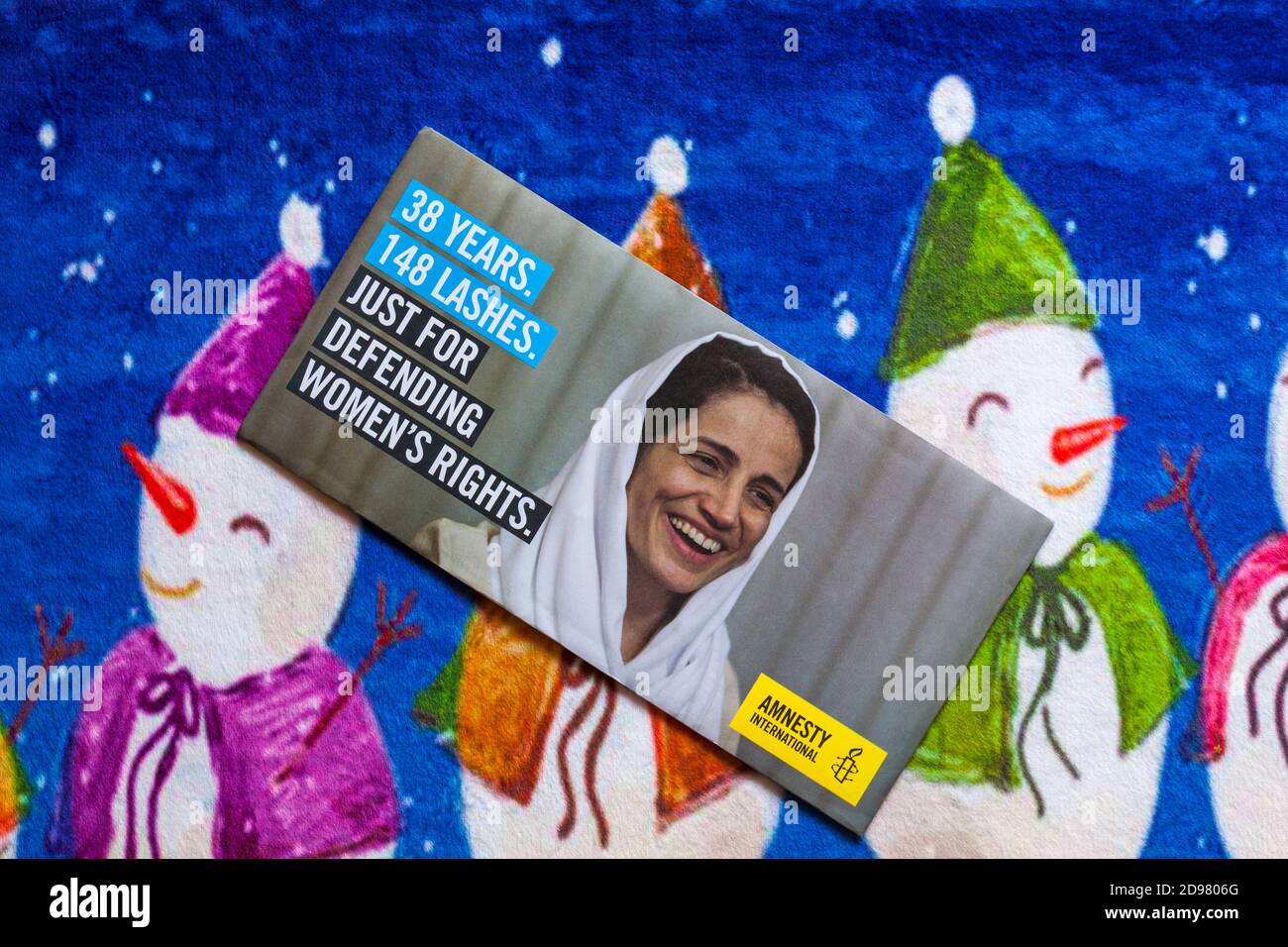 Post on Christmas mat - charity appeal, Amnesty International 38 years 148 lashes just for defending women's rights Stock Photo