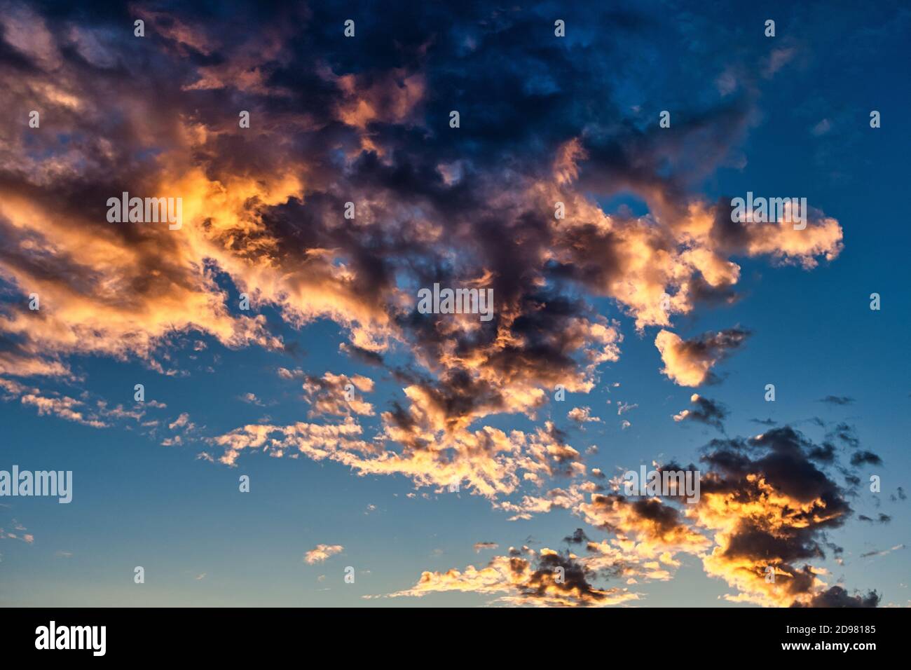 Epic sunset cloudscape with golden colors in blue sky. Stock Photo