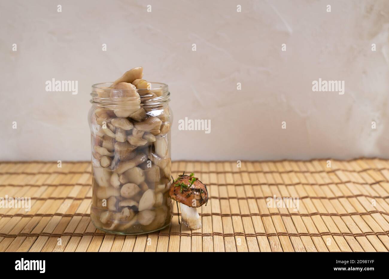 Pickled forest mushrooms in a glass jar on a wooden background. Autumn gifts. Horizontal orientation. Copy space. Stock Photo