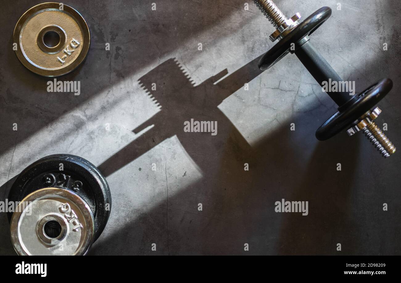 Dumbbells and various weight plates on a concrete surface. Background with empty space. Stock Photo