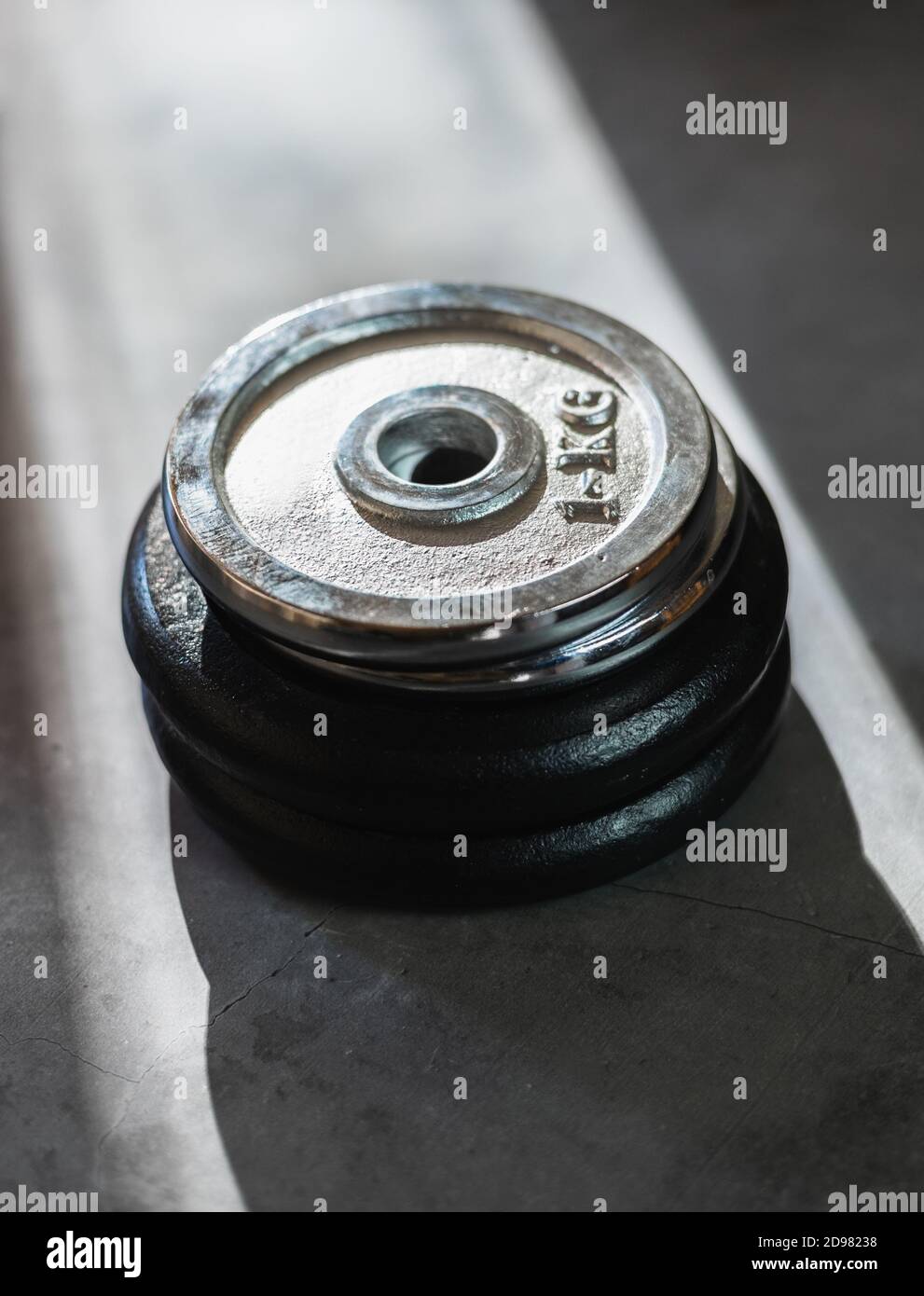 Iron weight plates of different sizes and weights stacked on a concrete