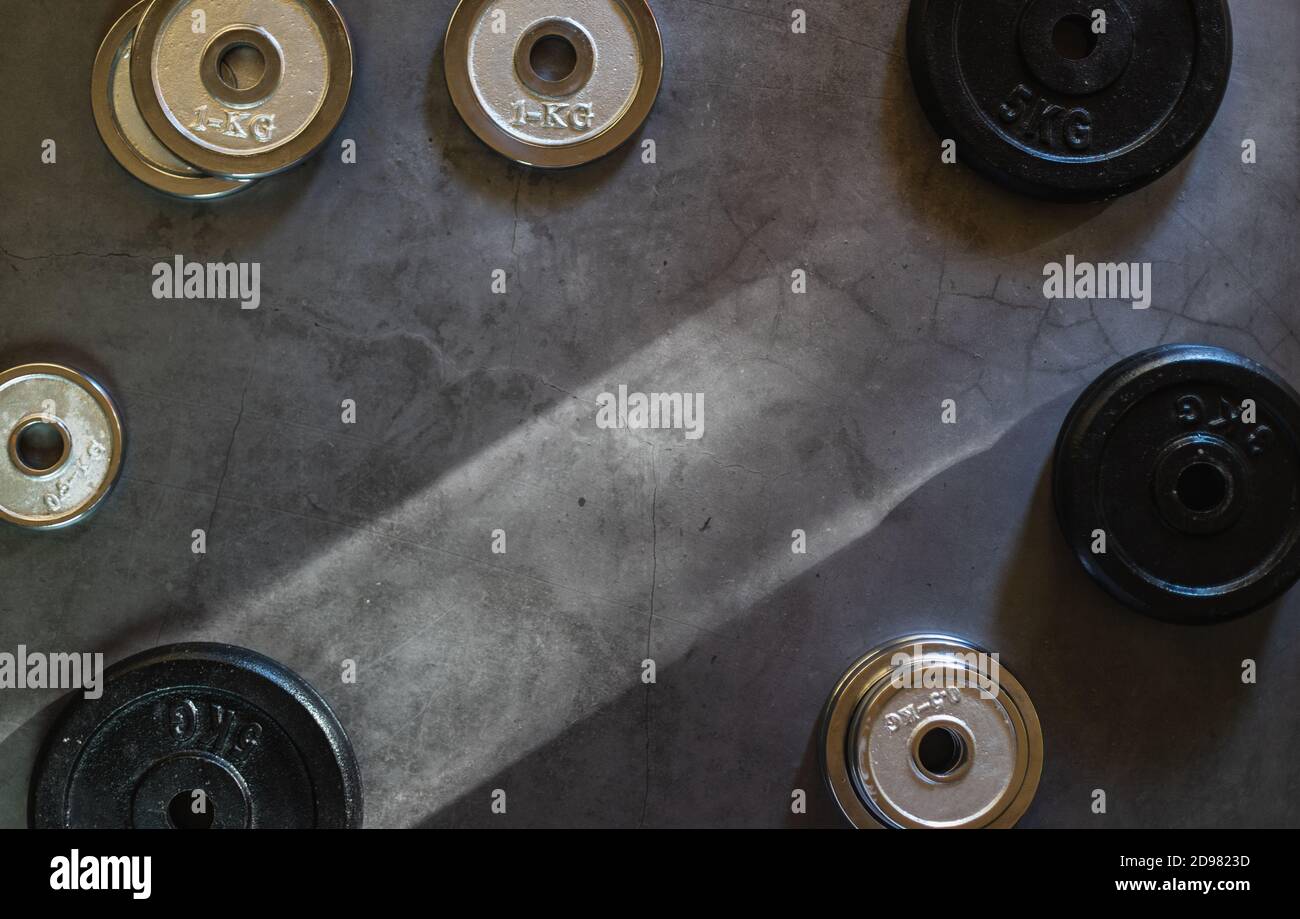 Weight plates of different weights, sizes and colors on a concrete