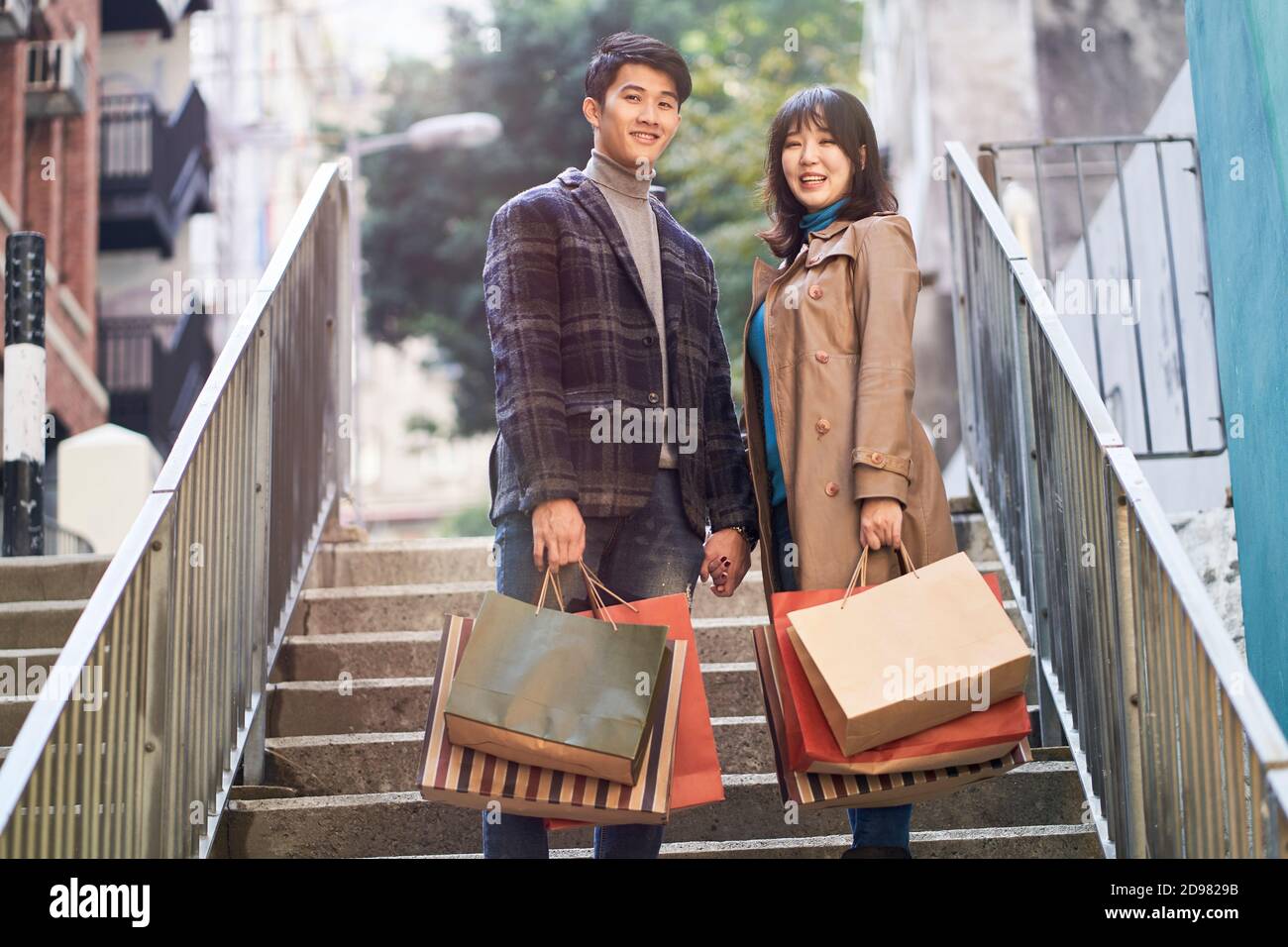 outdoor portrait of a happy young asian couple returning from a ...